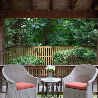 A cozy outdoor patio with wicker chairs and a small table overlooking a garden.