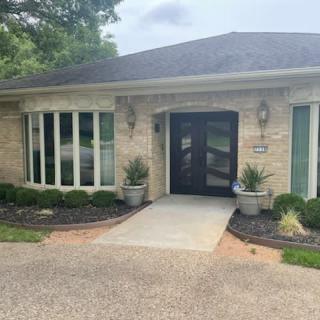 A brick house entrance with large windows and potted plants.