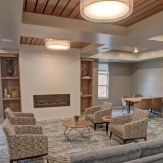 A modern living room with comfortable seating, a fireplace, built-in bookshelves, and a grand piano.