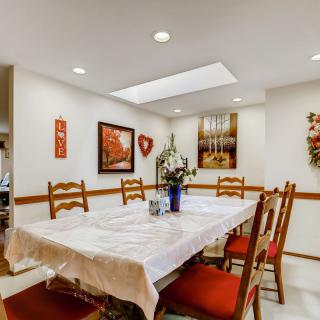 A cozy dining room with a table, chairs, and various artworks on the walls.