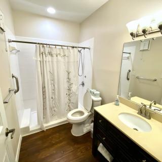 A clean and well-lit bathroom with a shower, toilet, and sink.