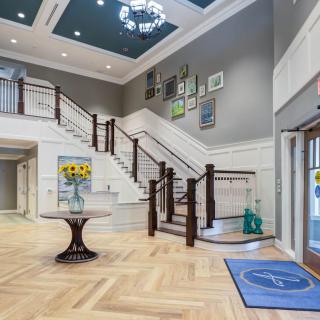 A stylish lobby with a central table, decorative art, and an elegant staircase.