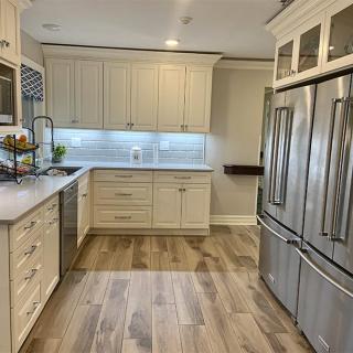 A modern kitchen with stainless steel appliances and wood flooring.