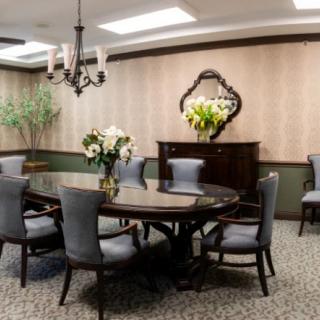 An elegantly designed dining room with a round table, cushioned chairs, and a chandelier.