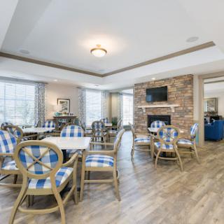 A modern dining area featuring stylish furniture, a stone fireplace, and ample natural light.
