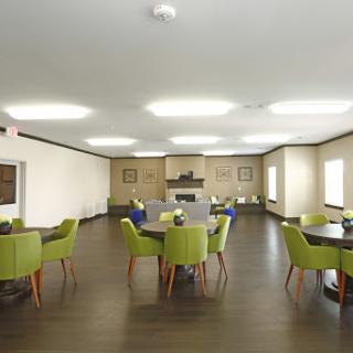 A spacious and modern dining area featuring green chairs and wooden tables.