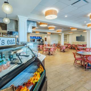 A bright and welcoming dining area featuring cozy seating arrangements and a food display counter.