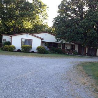 A residential house with a gravel driveway surrounded by trees.