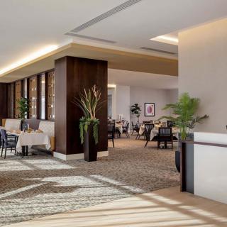 A modern and bright hotel lobby with sleek furniture and decorative plants.