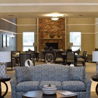 A cozy living room with a central sofa, coffee tables, and a brick fireplace in the background.
