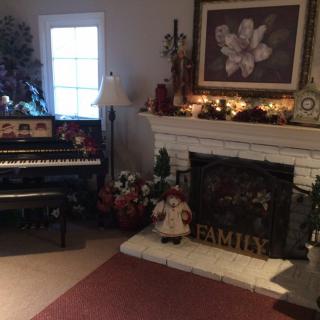 A cozy living room featuring a piano and decorated fireplace.