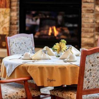A cozy dining setup with a neatly arranged table near a warm fireplace.