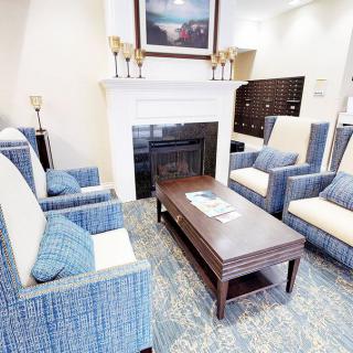 A cozy living room with blue armchairs and a coffee table in front of a fireplace.