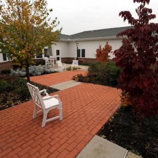 A peaceful outdoor patio with brick walkways and benches surrounded by trees and landscaping.