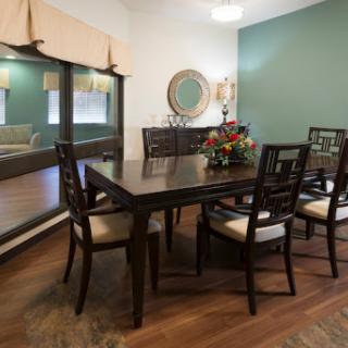 A cozy dining room featuring a wooden table and chairs, complemented by green walls and elegant decor.