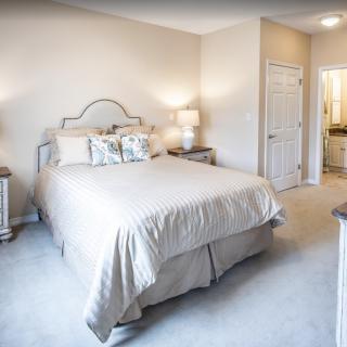A cozy bedroom with a neatly made bed, two nightstands, and elegant lighting.