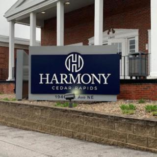 A sign for Harmony Cedar Rapids outside a brick building.