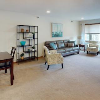 A cozy and inviting living room featuring a comfortable sofa, stylish armchair, and a dining table, all bathed in natural light.