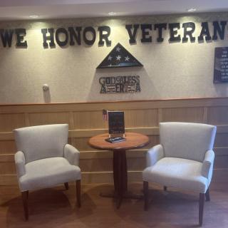 A cozy seating area honoring veterans, featuring chairs and a tribute display on the wall.
