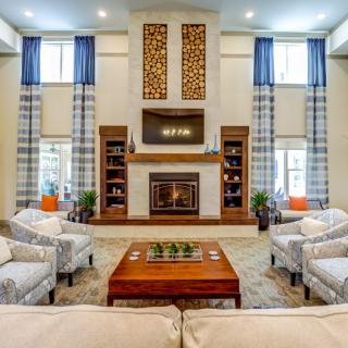 A spacious and elegantly designed living room featuring a central fireplace, comfortable sofas, and large windows with blue curtains.