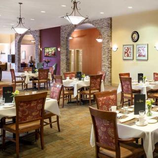 A cozy restaurant dining area with neatly arranged tables and chairs, adorned with elegant lighting and decor.