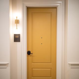 A luxurious hotel room door with an elegant light fixture in a hallway.