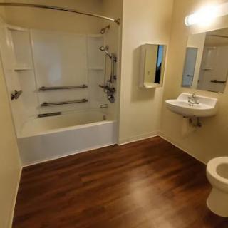 A clean and modern bathroom featuring a shower, toilet, and sink with wooden flooring.