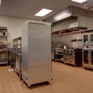 A well-equipped commercial kitchen with stainless steel appliances and storage shelves.