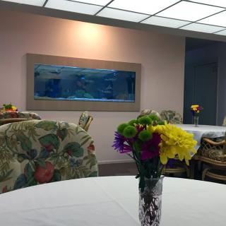 A cozy lounge area featuring an aquarium on the wall and vibrant flowers on the table.