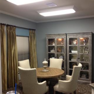 A cozy dining area featuring a round table and stylish chairs, complemented by elegant curtains and display cabinets.