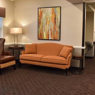 A cozy living room with a warm-toned sofa, abstract artwork on the wall, and a standing lamp.