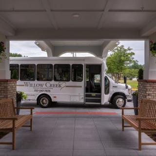 A shuttle bus parked at a building entrance with benches on either side.
