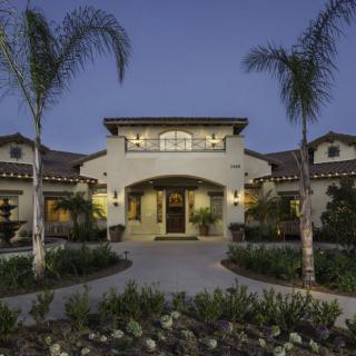 A luxurious house exterior with palm trees and well-maintained landscaping during the evening.