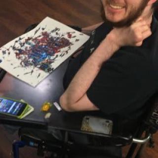 A person in a wheelchair smiling while working on an abstract painting.