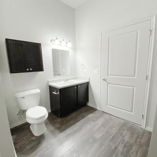 A modern, minimalist bathroom with a toilet, sink, and mirror.