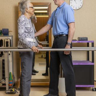 An elderly person receiving assistance from a therapist during a physical therapy session.