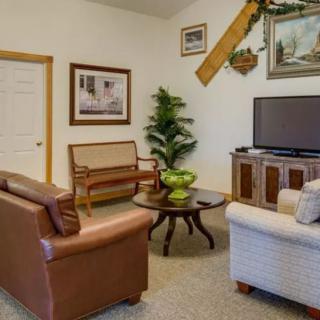 A cozy living room setup featuring a sofa, armchair, and a TV alongside decorative elements.