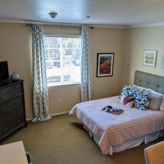 A neatly decorated bedroom with a bed, dresser, and artwork on the walls.
