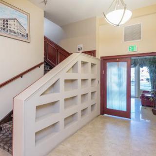 A well-lit lobby area featuring a staircase, built-in shelves, and an entrance door.