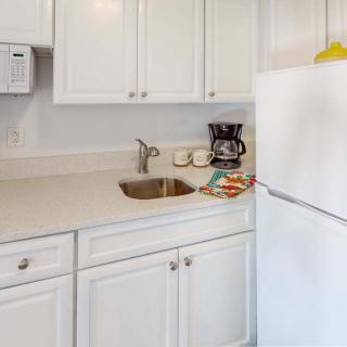 A clean and minimalistic kitchen with white cabinets and a coffee maker on the countertop.