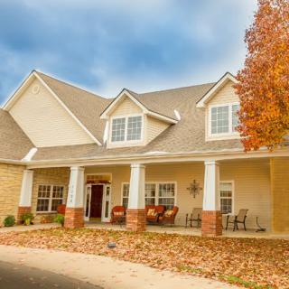 A suburban house with a front porch surrounded by autumn leaves and trees.