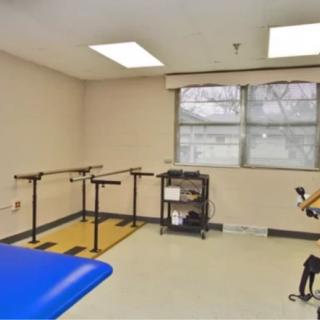 A physical therapy room featuring parallel bars and therapy equipment.