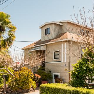 A charming residential house surrounded by lush greenery on a sunny day.