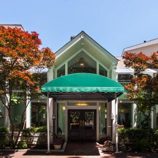 A front view of a building with a green awning, surrounded by trees.