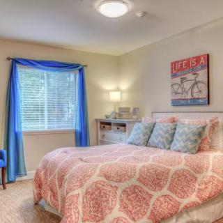 A cozy bedroom with a patterned bedspread and bright blue curtains.