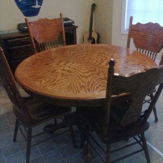 A wooden dining table with four matching chairs in a kitchen setting.