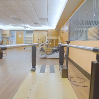 A physical therapy room featuring parallel bars for rehabilitation exercises.