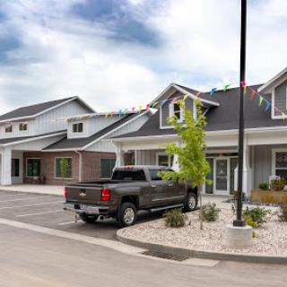 A modern residential complex with a truck parked in front and well-maintained landscaping on a cloudy day.