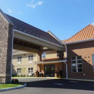 A view of the entrance of a modern building with stone and brick exterior under a clear blue sky.