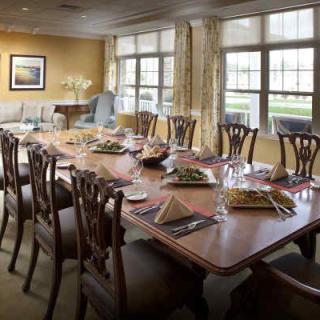 An elegantly set dining table with chairs in a well-lit room with large windows.